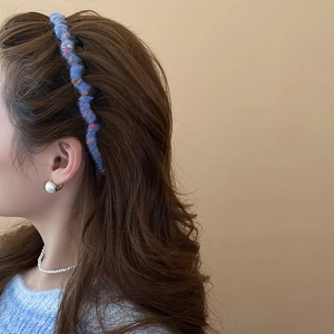 Detail of blue knitted wool headband showing textured wave pattern on a female model