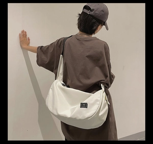 Close-up of white waterproof nylon gym bag with wide shoulder strap and woven patch