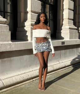 Detail of white knit off-shoulder crop top and silver sequin mini skirt set