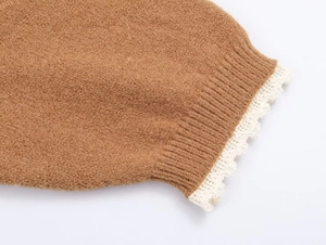 Gros plan d'un poignet de pull en maille marron avec texture côtelée et bord en dentelle