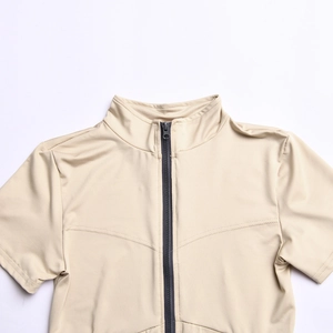Close-up of beige short sleeve bodysuit featuring a dark grey front zipper and stand collar