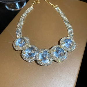 Detailed close-up of gold chain necklace featuring five large rhinestones with halo settings