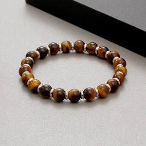 Detailed top view of 8mm yellow tiger eye stone beads with silver metal spacers on a grey surface