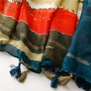 Détail d'une écharpe en voile rayée avec fils dorés et franges à glands élégantes