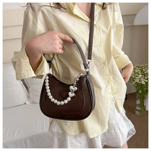 Detailed view of deep brown heart purse with pearl handle and silver heart charms