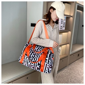 Detail view of large travel bag with black white graffiti and orange straps