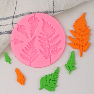 Detailed pink silicone mold for fern leaf fondant with finished green and orange leaf deco