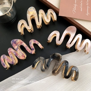 Elegant wave-shaped acetate hair claws with gold metal teeth in four marble colors