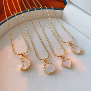 Elegant gold necklaces with shell-inlaid heart and moon pendants in a luxury gift box