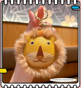 Detail of a handmade lion plush keychain with yellow leather and gold metal ring