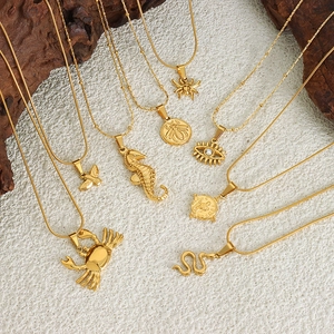 Golden statement necklaces with crab, snake, and evil eye pendants on a textured stone base