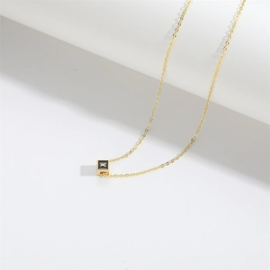 Detailed view of a gold square letter X pendant on a delicate minimalist chain