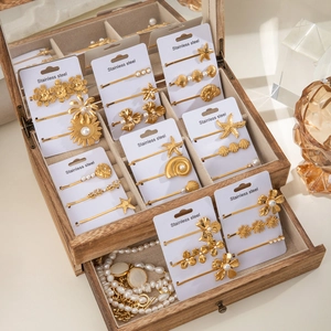 Coffret de barrettes dorées en acier inoxydable avec perles et fleurs sur support en bois