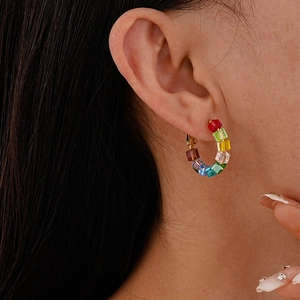 Close-up of rainbow crystal C-shaped hoop earrings with square stones on a gold base