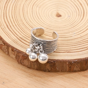 Macro view of textured vintage silver multi-layer open ring with three bead charms on wood
