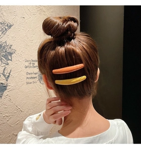 Detail of yellow and orange seamless hair side combs worn on a woman's hair
