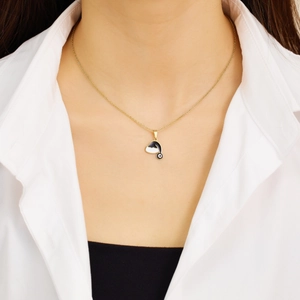 Detail of gold titanium steel necklace with black and white enamel hat pendant on a model