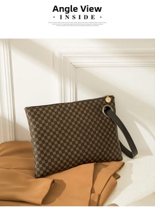 Detail of a brown crocodile pattern clutch bag with gold zipper and leather wristlet