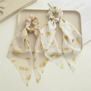 Two chiffon scrunchies with long streamers and gold feather patterns in beige and white