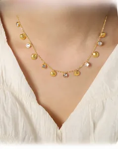Detail of 18K gold shell pendant and zircon stones on a layered seaside necklace