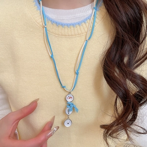 Vue rapprochée du collier bonhomme de neige avec écharpe à pompons sur pull en maille