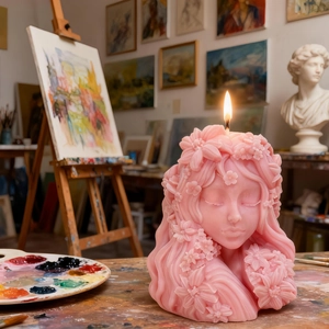 Pink sleeping girl candle with flower details lit in a creative artist studio setting