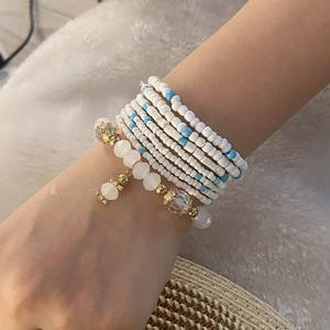 Detail of bohemian multilayered beaded bracelet with white, blue and gold beads on model
