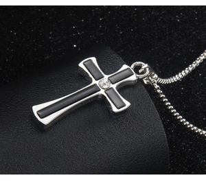 Close-up of silver cross necklace with black inlay and a sparkling center stone