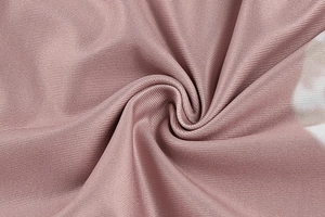 Macro view of dusty rose ribbed stretch fabric showing soft texture and subtle sheen