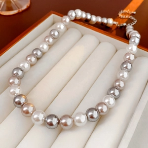Detail of white, gray, and champagne pearl necklaces in a beige velvet jewelry box