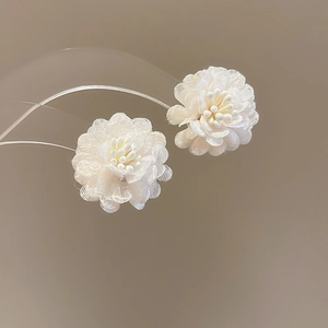 Close-up of sweet white fabric flower stud earrings with delicate center stamens