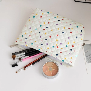 Quilted white cosmetic bag with colorful dots showing makeup brushes and palettes inside