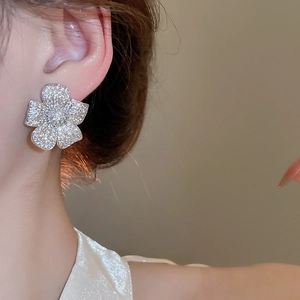 Close-up of five-petal flower earrings with micro-paved zircons worn by a model