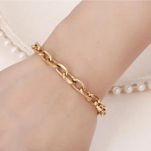 Elegant gold chunky chain link bracelet in polished finish worn on woman's wrist