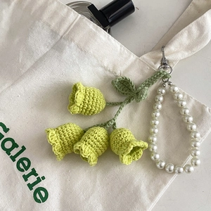 Detail of crochet lily of the valley charm with white pearls on a canvas bag handle
