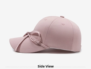 Side view of a light pink baseball cap with a ribbon bow detail and neat stitching