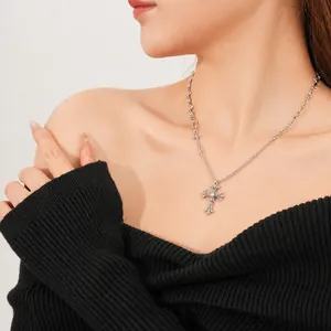 Silver safety pin zircon cross necklace for women on minimalist black sweater background
