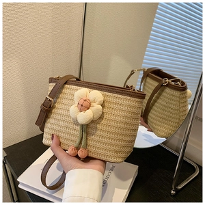 Close-up of woven straw bucket bag with white floral accent and brown leather trim detailing
