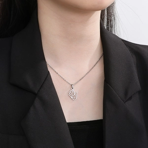 Close-up of a silver hollow palm pendant with heart design worn on a female model