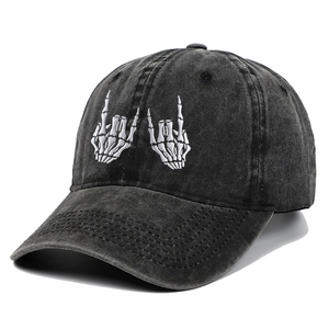 Detailed close-up of white skeleton hand embroidery on black washed cotton baseball cap