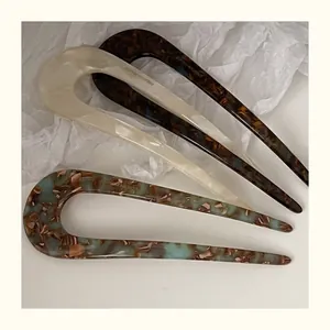 Detailed close-up of three acetate U-shaped hair pins in marble and tortoiseshell patterns