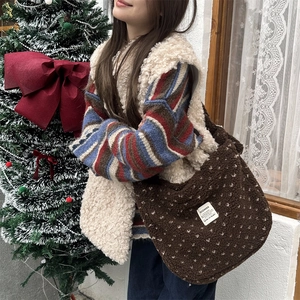 Detailed texture of brown plush crossbody bag with white floral pattern and woven label