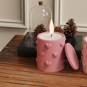 Pink heart embossed cylindrical candle jar with lid placed on a textured wooden table
