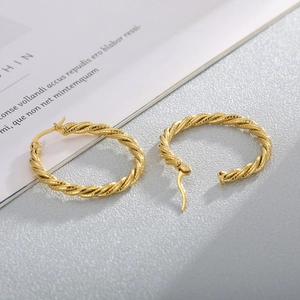 Detailed view of large gold twisted rope earrings with intricate braided metal texture