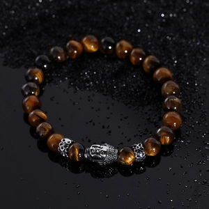 Macro shot of tiger eye beads with silver Buddha head and hollow metal spacers on black