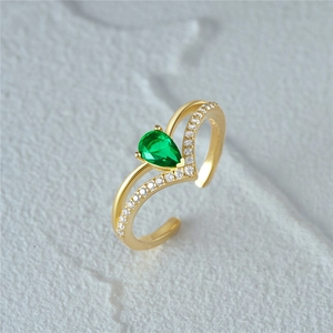 Macro shot of gold teardrop ring with green gemstone and micro-pave diamond accents