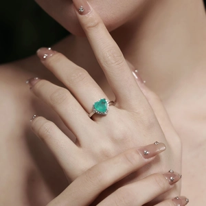 Macro detail of a 925 silver heart-shaped emerald green zircon ring worn by a model
