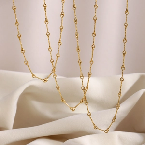 Close-up of elegant 18K gold plated jointed chain necklaces on soft white fabric