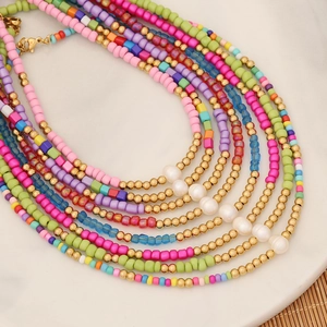 Detail of colorful seed bead necklace with white pearls on white marble surface