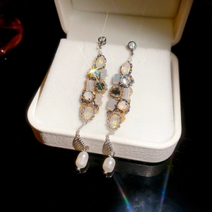 Macro view of long tassel earrings with colorful opal and white pearl in a gift box
